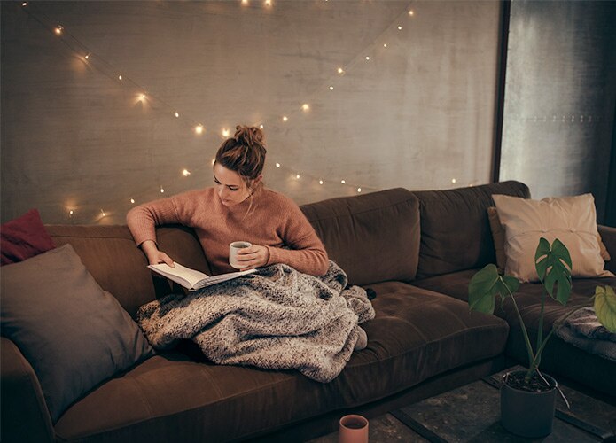 Woman reading on sofa with blanket