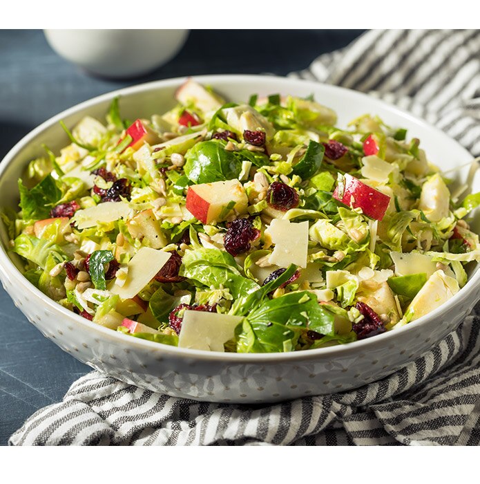 Raw brussels sprouts in a salad with apples, cranberries and cheese