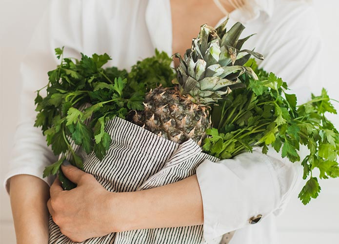 Woman holding bag of pineapple and herbs