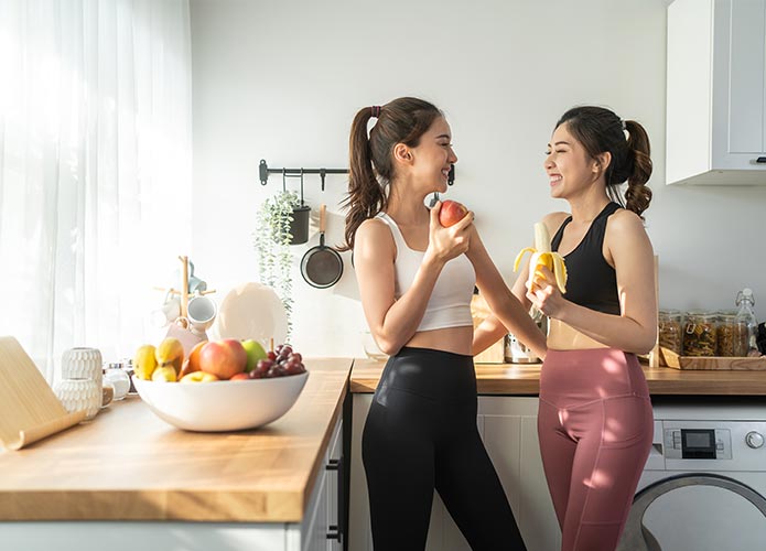 Women eating fruit in kitchen