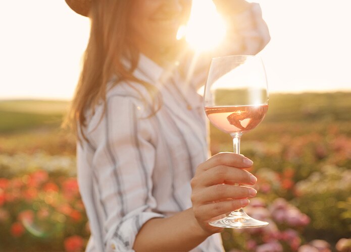 Woman holding glass of rose in sun