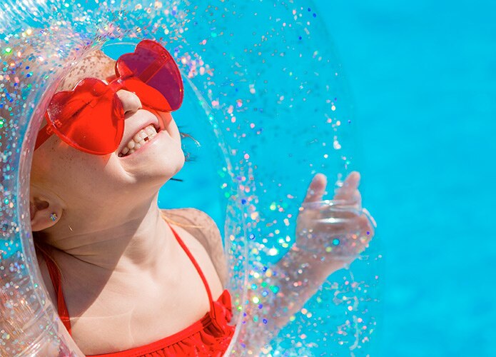 Child smiling at sun with floating device