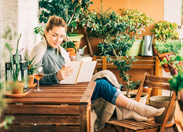 Woman reading book on balcony with plants