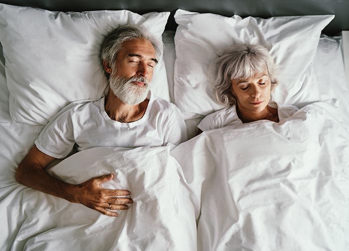 Elderly couple sleeping in bed