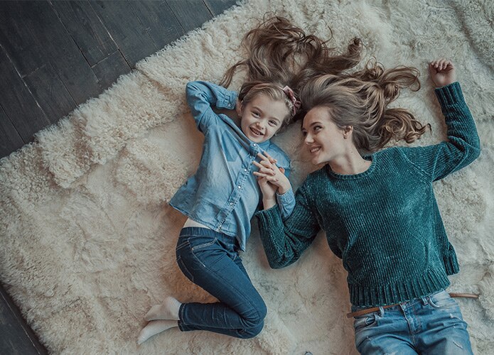 Girl and woman laying on rug