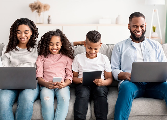 Family using devices sitting on lounge